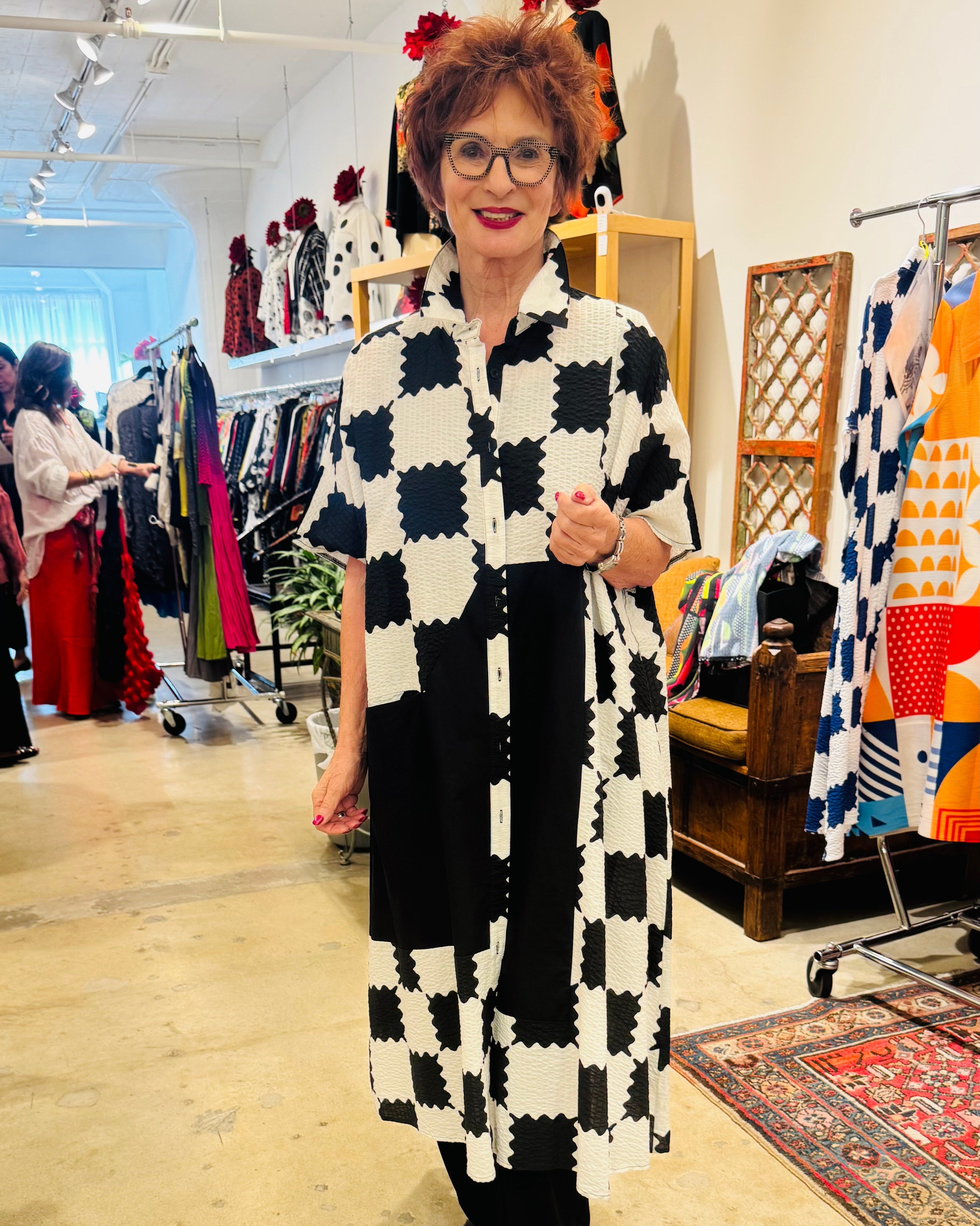 Woman wearing a black and white checkered coat in a clothing store.