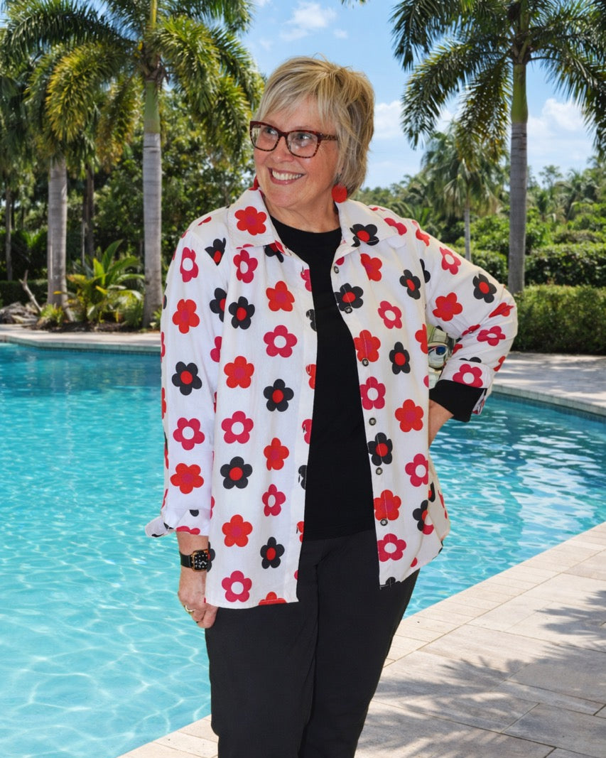 Woman wearing a floral jacket by a pool with palm trees in the background
