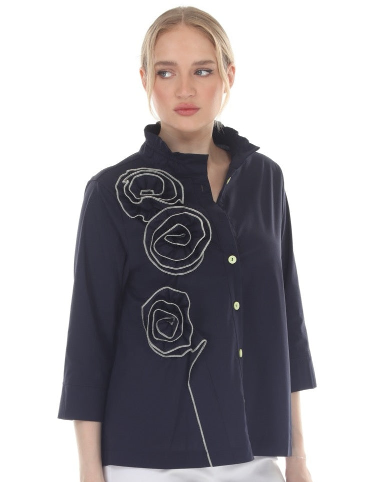 Woman wearing a navy blue coat with white floral embroidery on a white background