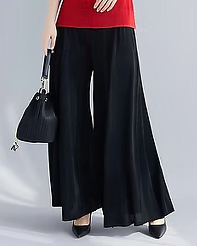 Woman wearing a red top and black wide-leg pants on a gray background