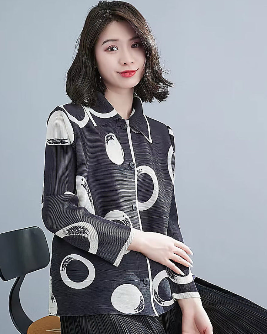 Woman wearing a black and white patterned jacket against a gray background