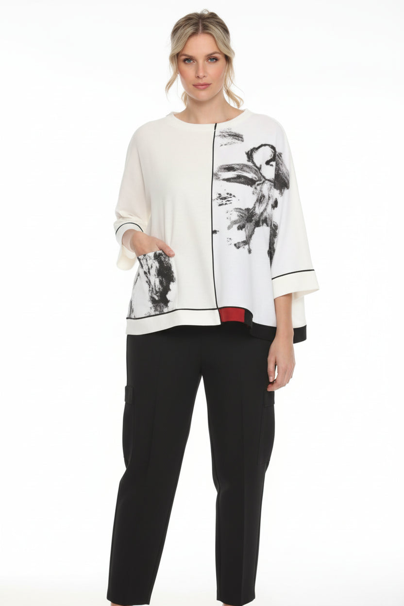 Woman wearing a white blouse with black floral patterns on a plain background