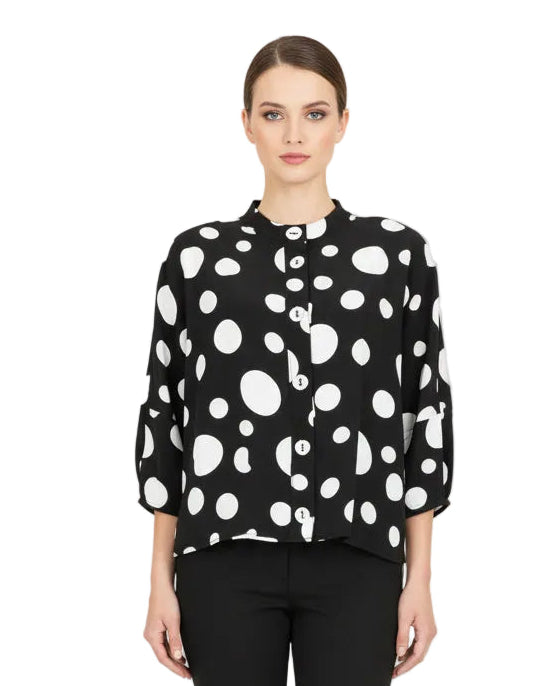 Woman wearing a black and white polka dot blouse with black pants on a white background