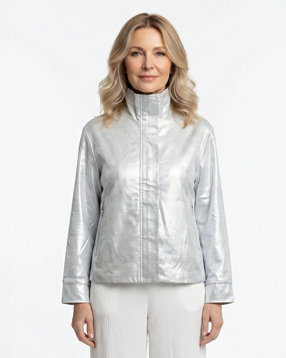 Woman wearing a silver metallic jacket zipped up and white pants on a white background
