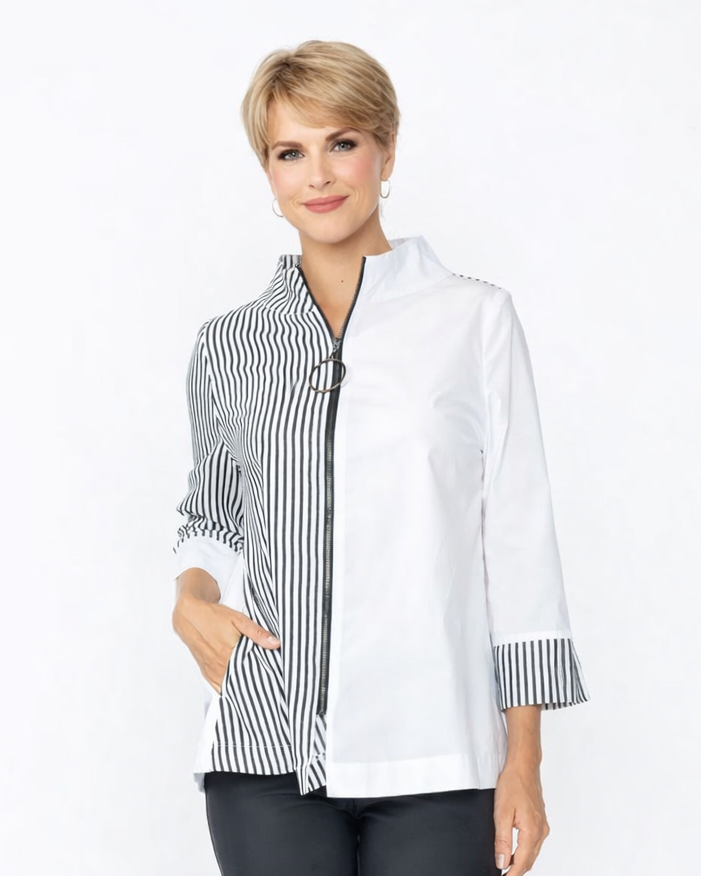 Woman wearing a white blouse with black and white striped cuffs and trim, paired with dark pants on a white background.