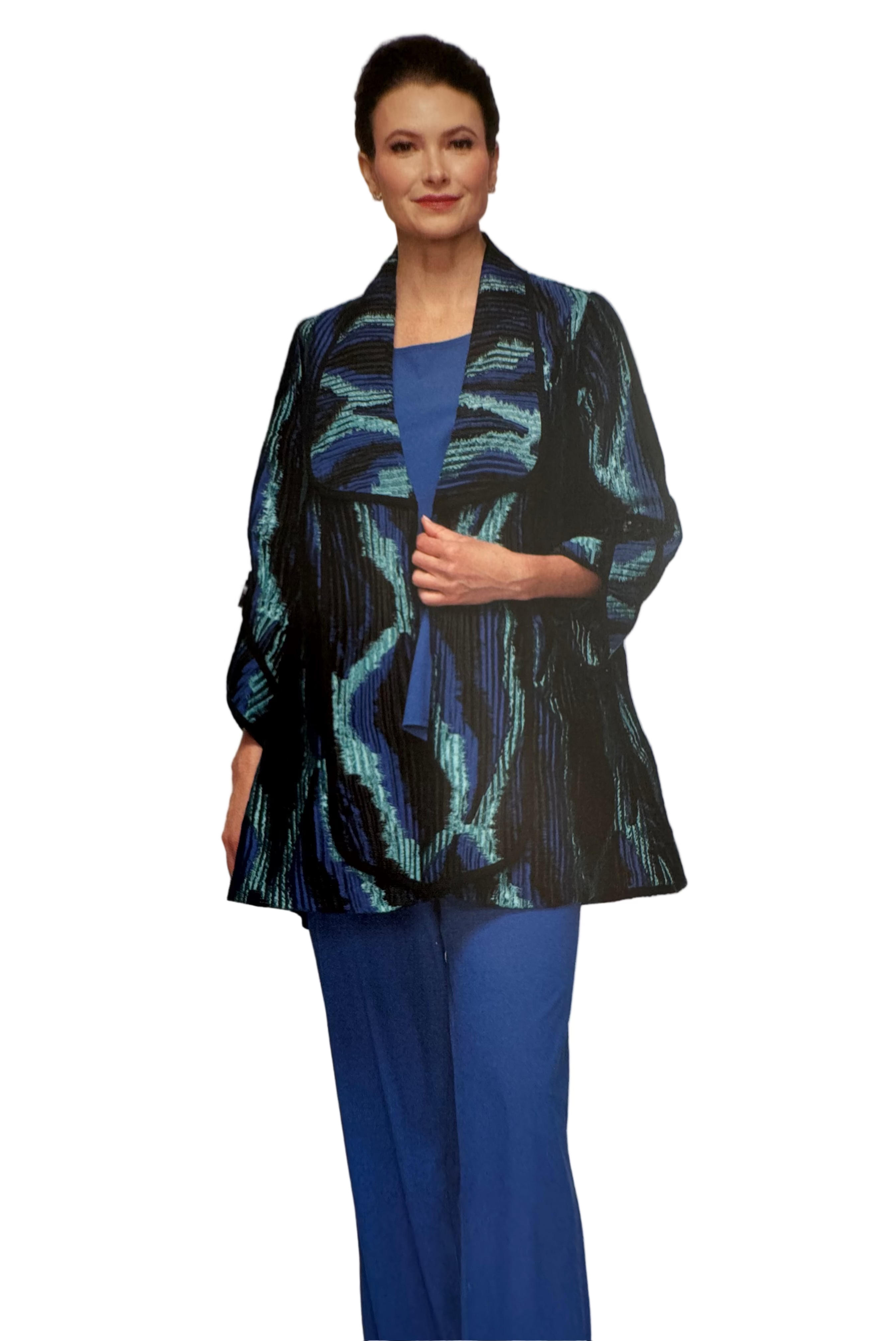 Woman wearing a patterned jacket over a blue top and pants on a plain background