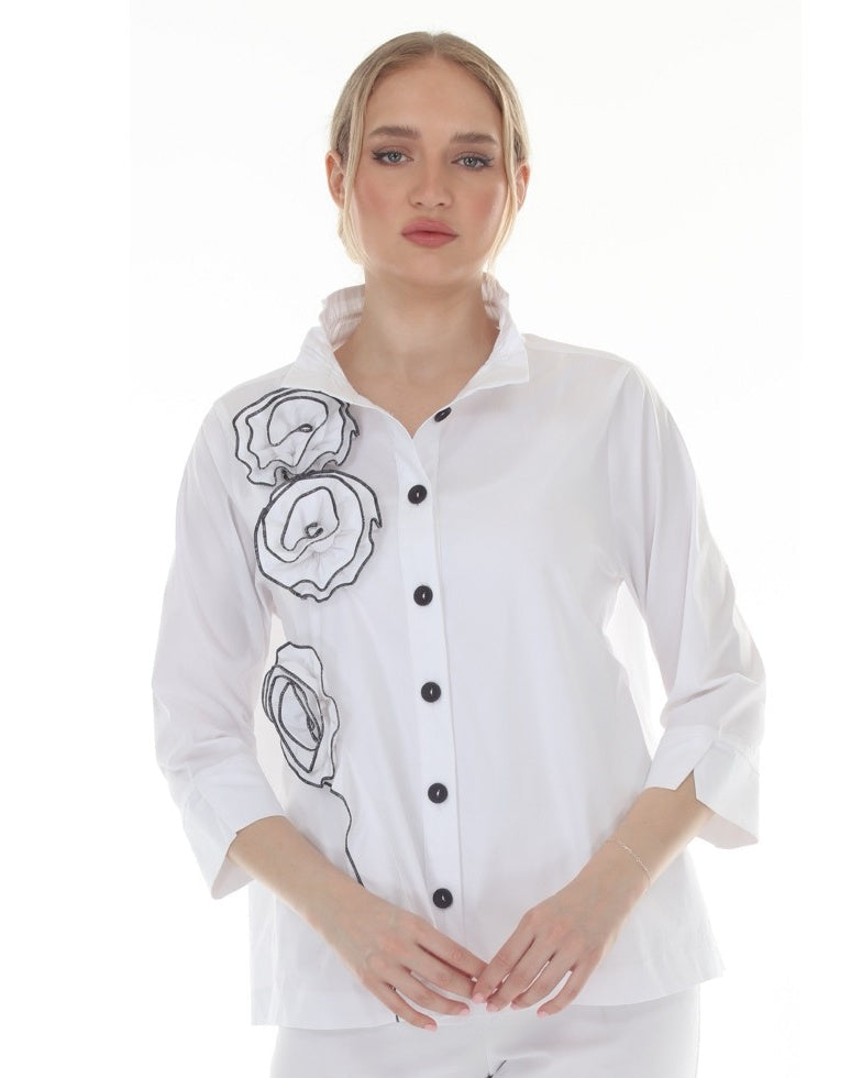 Woman wearing a white shirt with black designs and buttons on a white background