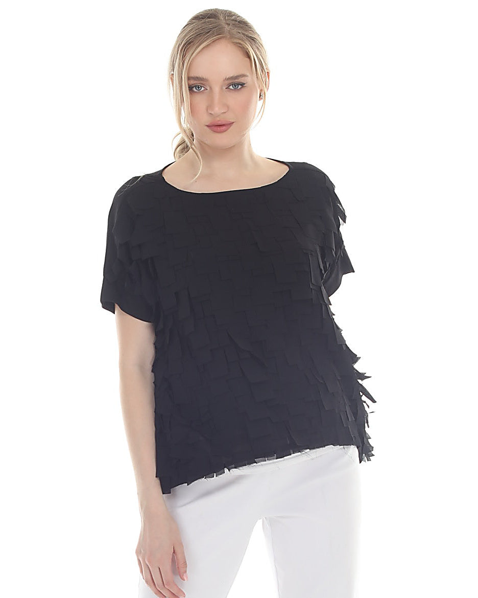 Woman wearing a black fringed top and white pants on a white background